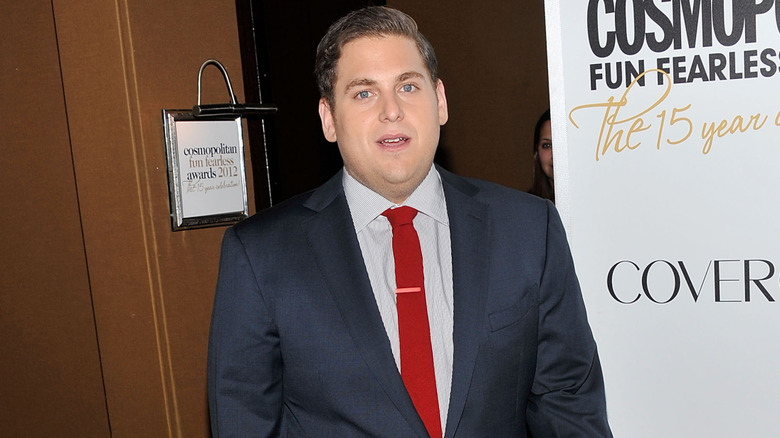 Jonah Hill attends an event in a dark suit with a red tie