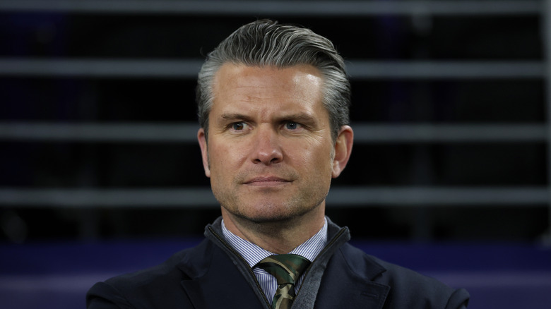 U.S. Secretary of War Pete Hegseth looking on in the distance