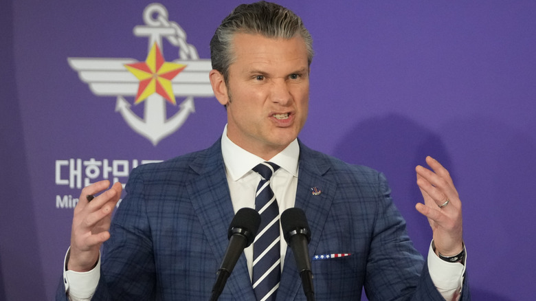 Pete Hegseth speaks animatedly on stage in a blue pinstriped suit