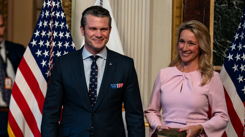 Pete Hegseth and wife Jennifer Hegseth in front of American flags.