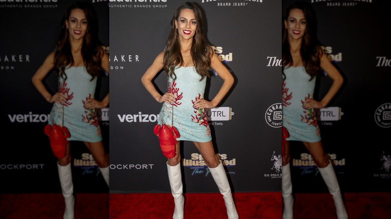 Jordon Hudson posing on the red carpet in a pale blue minidress with red coral designs