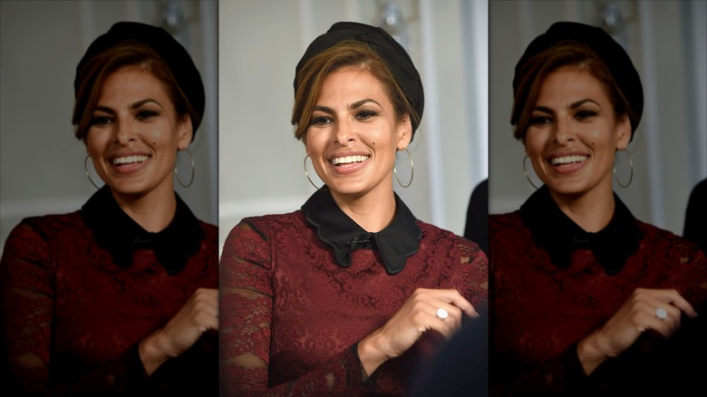 Eva Mendes smiling with teeth in a maroon shirt and black headband