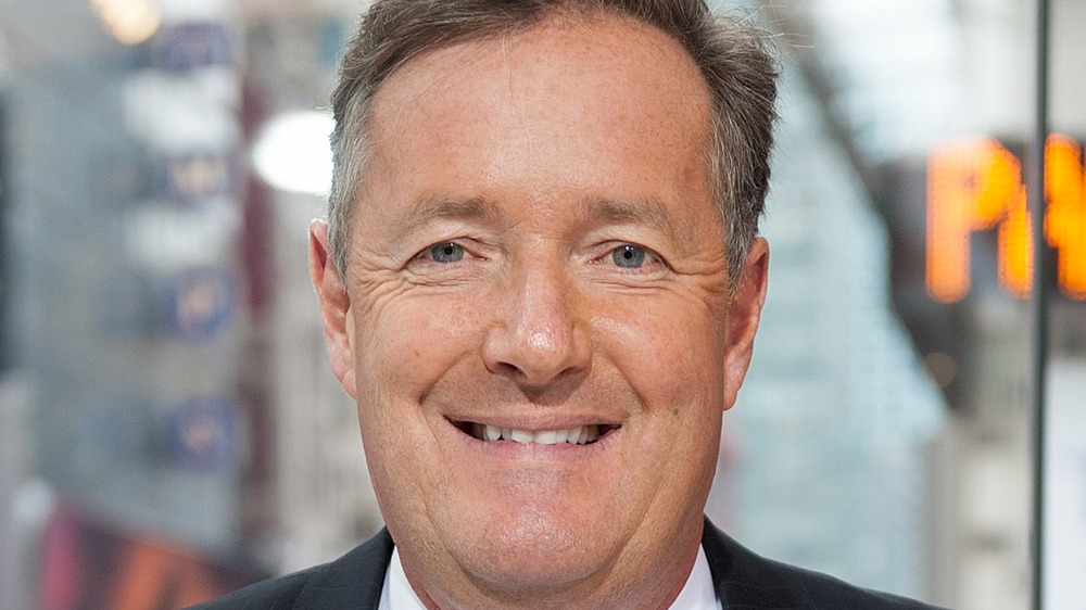 Piers Morgan grins at the camera while taking a photo-op in New York