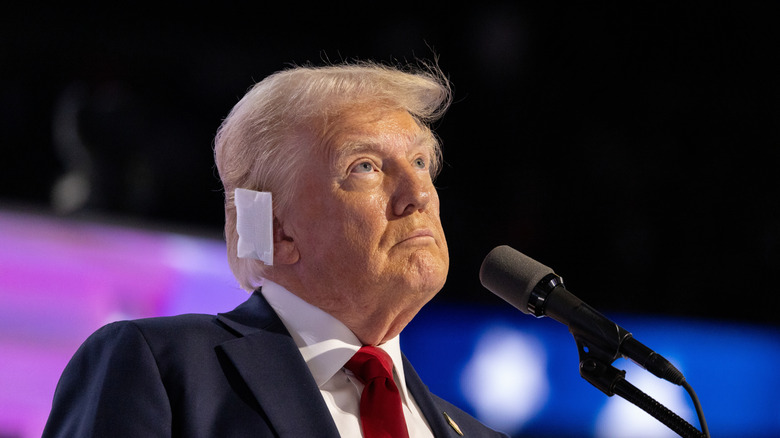 Donald Trump onstage looking pensive with an ear bandage