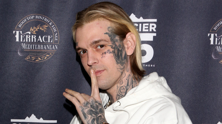 Aaron Carter posing with finger to lips, face tattoos