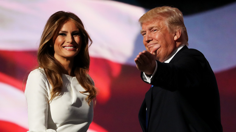 Melania Trump smiling as Donald Trump gestures