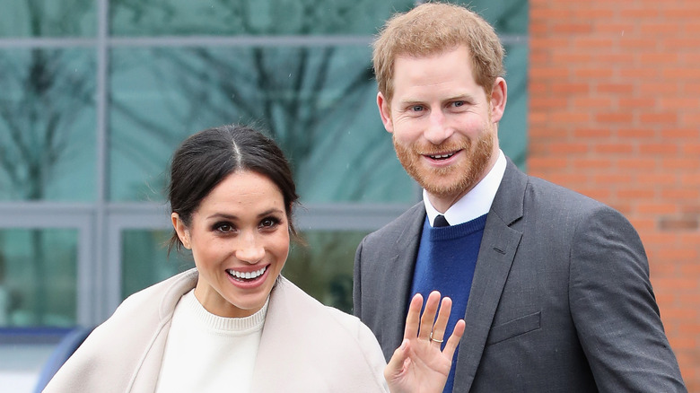 Prince Harry and Meghan Markle smiling and waving.
