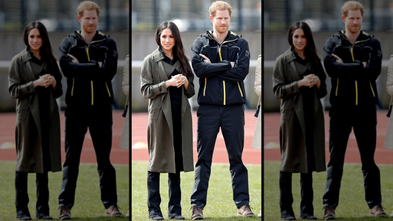 Prince Harry and Meghan Markle standing beside each other outside on a track field.