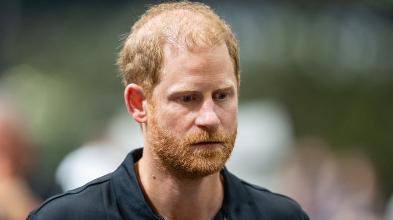 Prince Harry looking solemn in a black collared shirt