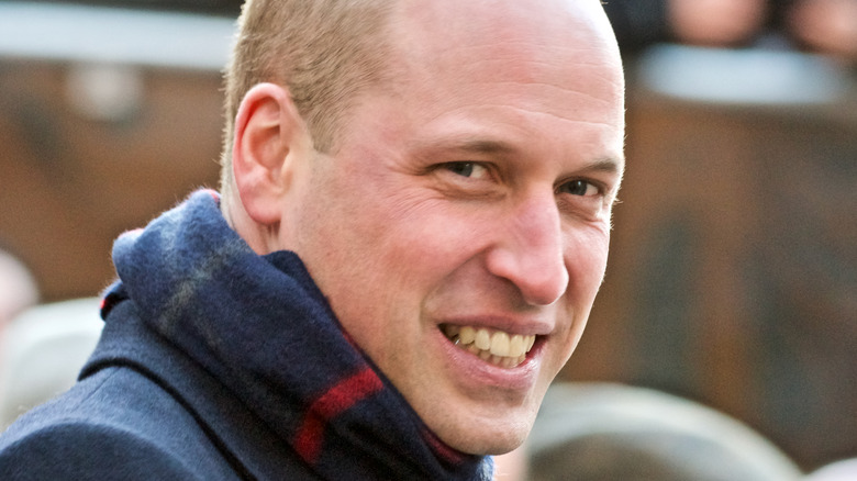 Prince William smiling and wearing plaid scarf