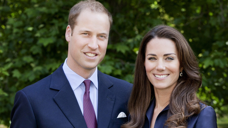 Prince William and Kate Middleton smiling in front of trees