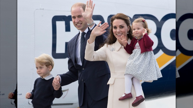 Charlotte waves to the crowds while held by Kate