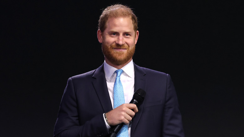 Prince Harry wearing a blue tie and suit on stage