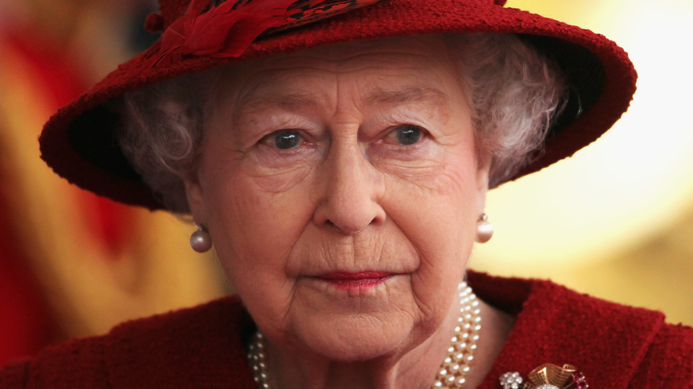 Queen Elizabeth looking stern in a hat and pearls