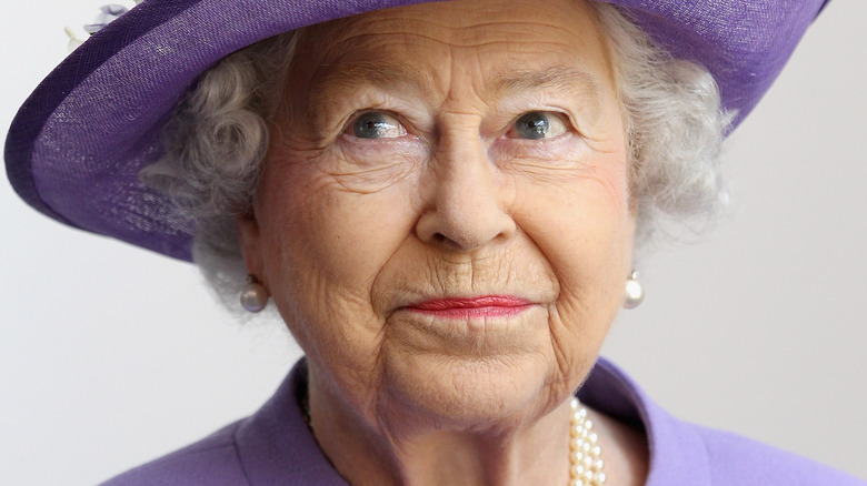 Queen Elizabeth smiling cheekily purple hat