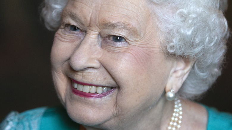 Queen Elizabeth Ii smiles in pearl earrings and necklace