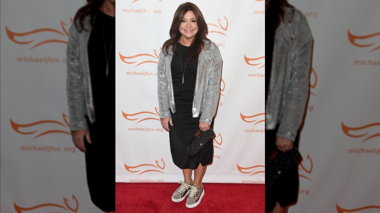 Rachael Ray with a silver jacket, black dress, and sneakers.