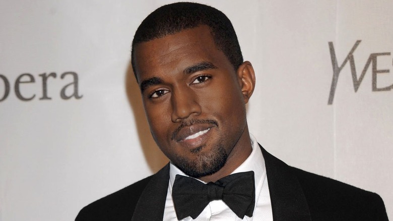 Kanye West wearing a tuxedo , smiling