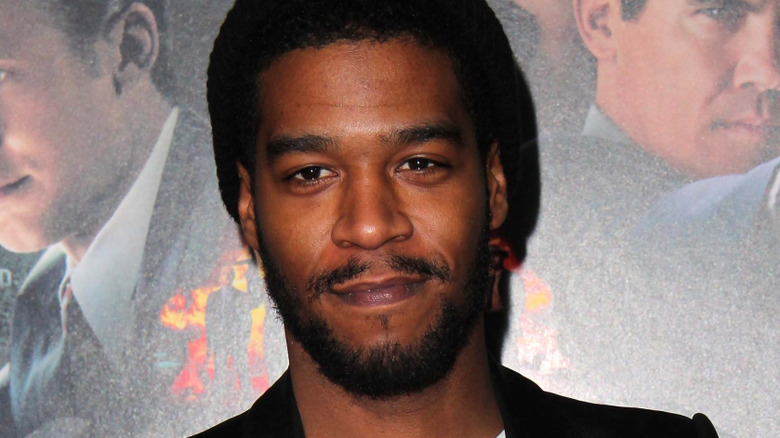 Kid Cudi standing in front of a movie poster