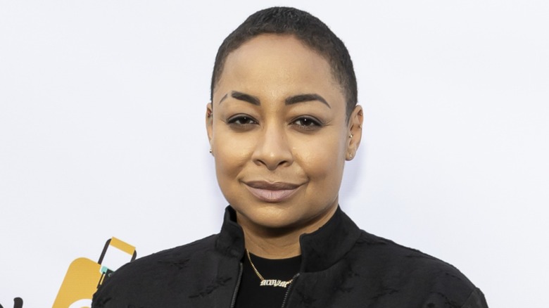 Dressed in an all-black jacket and shirt, Raven-Symoné gives the camera a piercing gaze.