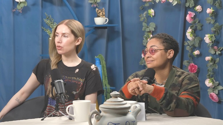 Raven-Symoné and Miranda Maday glance sideways while seated in behind microphones.