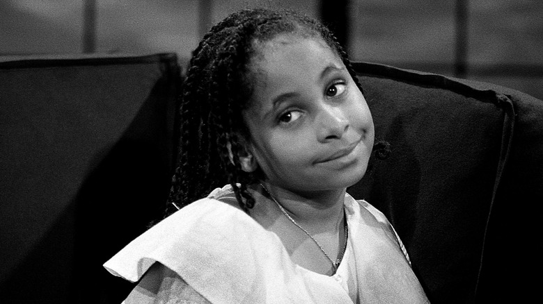 Young Raven-Symoné tilts her head to the side and smiles subtly.