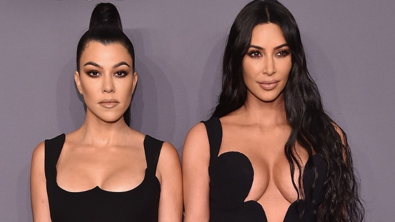 Kourtney and Kim Kardashian standing together
