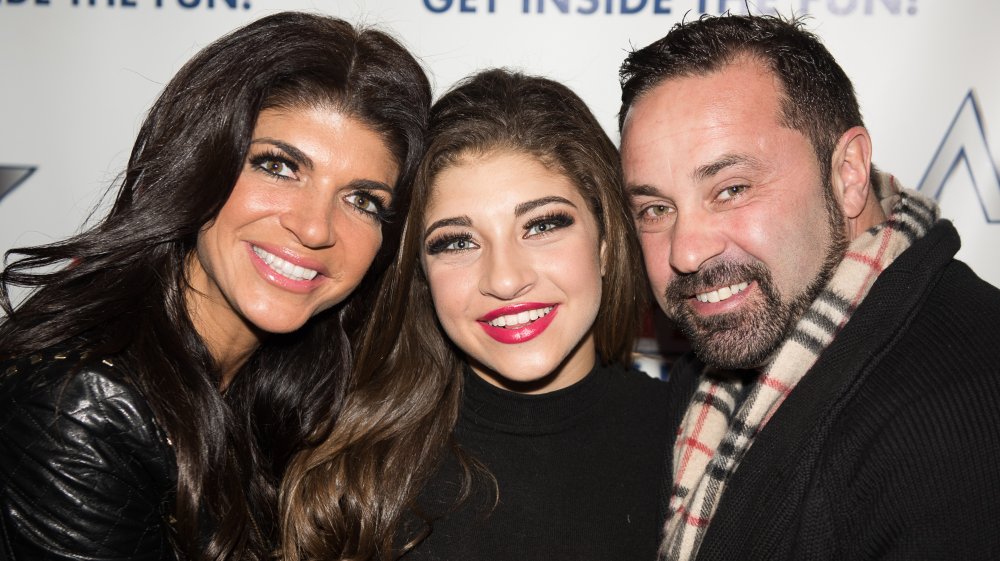 Teresa Giudice, Gia Giudice, and Joe Giudice smiling and embracing at a red carpet event 