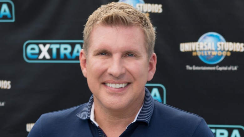 Sporting a navy blue shirt, Todd Chrisley is all smiles while staring at the camera..