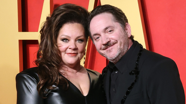Melissa McCarthy and Ben Falcone posing in matching black outfits.