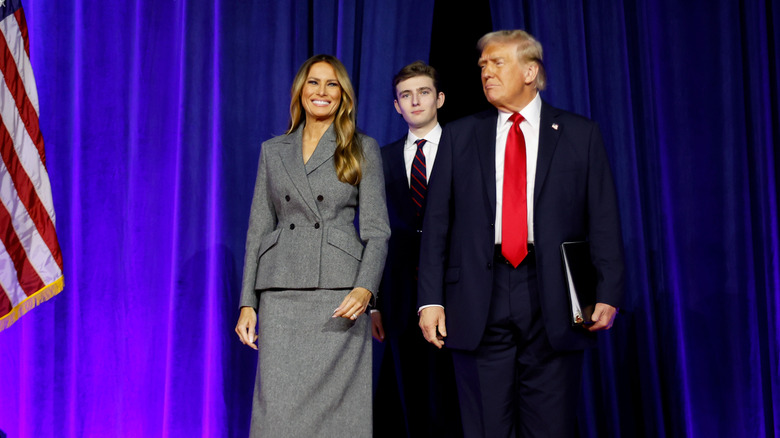 Melania Trump, Barron Trump, and Donald Trump standing on a stage