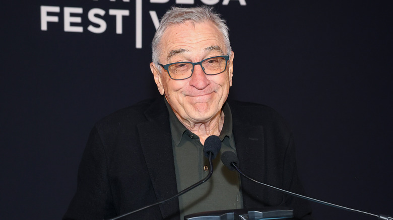 Robert De Niro smiling behind microphone
