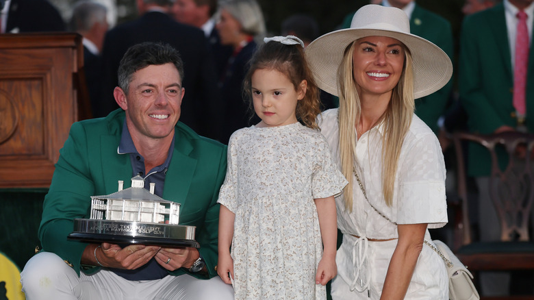 Rory McIlroy and Erica Stoll posing with their daughter