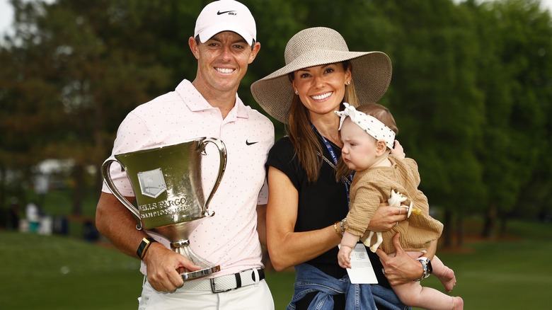 Erica Stoll and Rory McIlroy posing with their daughter