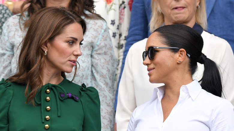 Kate Middleton and Meghan Markle photographed looking at each other at an event.