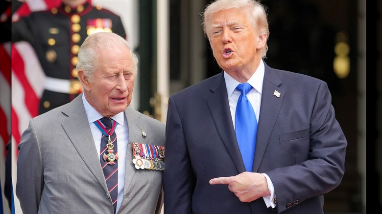Donald Trump speaking as he points to a squinting King Charles III.