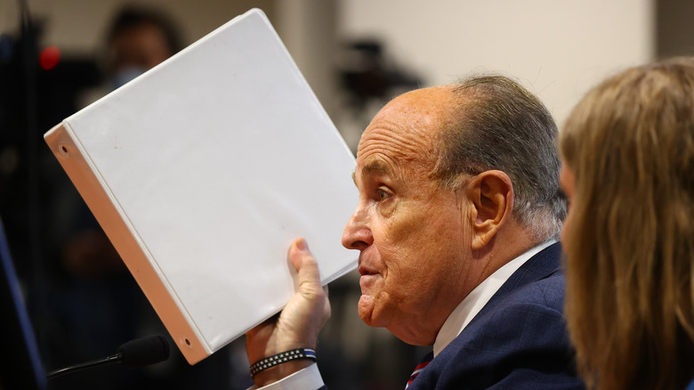 Rudy Giuliani holding binder in court