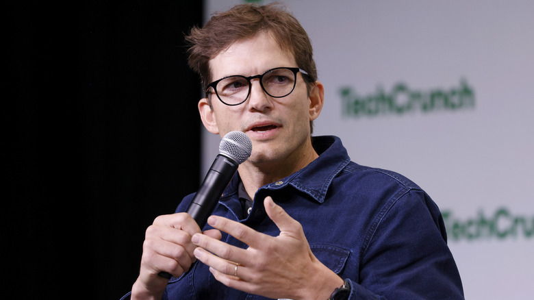 Ashton Kutcher wearing glasses speaking into mic