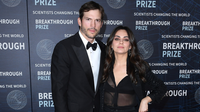 Ashton Kutcher and Mila Kunis posing on step-and-repeat