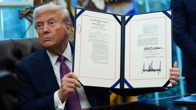 Donald Trump holding up an executive order with his signature