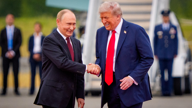 Donald Trump laughs and shakes hands with Vladimir Putin