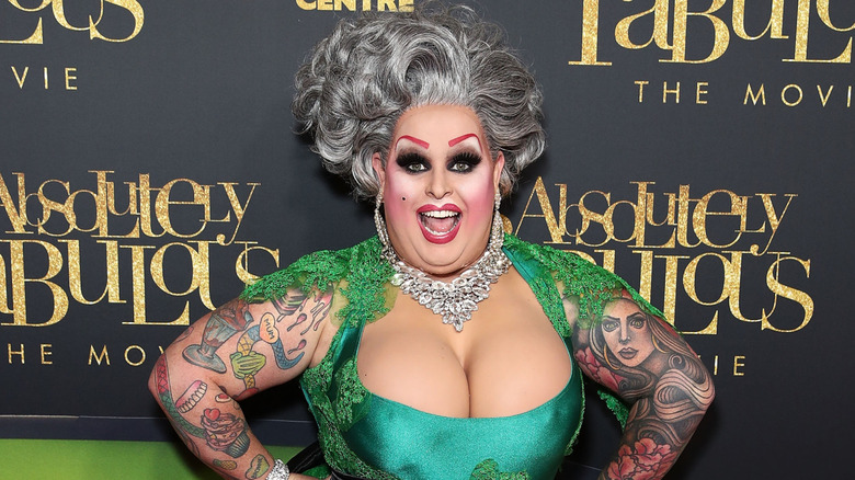 Drag queen Maxi Shield wearing a low cut green embellished dress on the red carpet