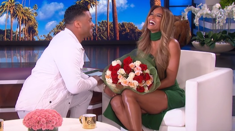 Russell Wilson kneeling in front of Ciara