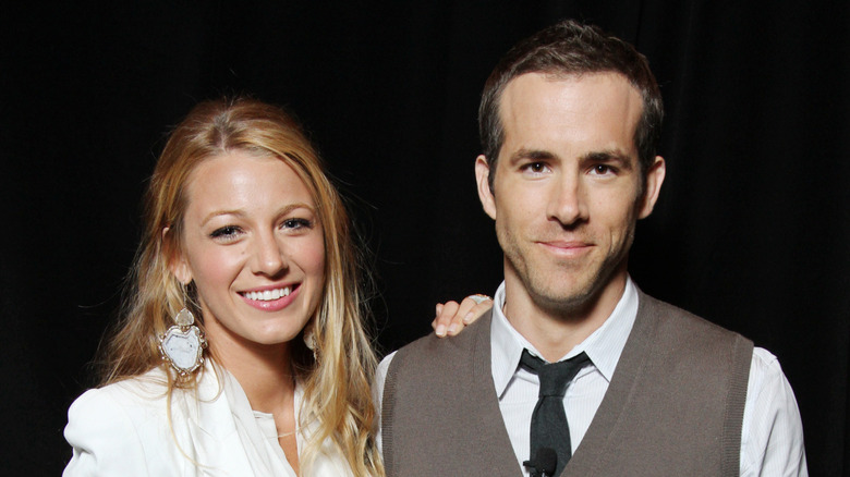 Blake Lively posing with a hand on Ryan Reynolds' shoulder in 2011