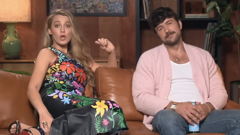 Blake Lively sits next to Brandon Sklenar on a couch