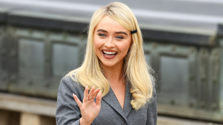 Sabrina Carpenter waves to photographers ahead of a Dior menswear fashion show