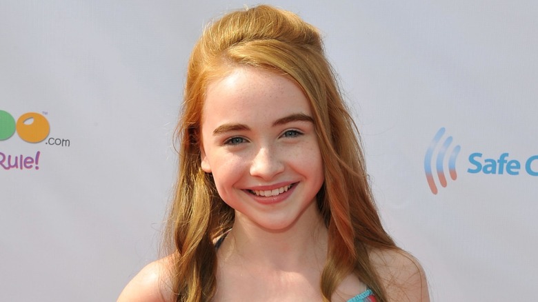 Sabrina Carpenter posing on the red carpet with red hair