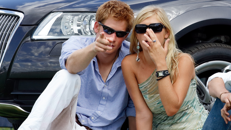 Chelsy Davy and Prince Harry stare down paparazzi while sitting on the grass.