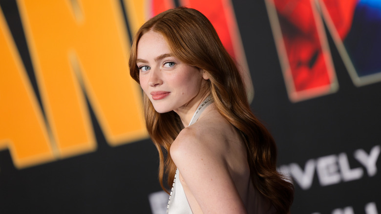 Sadie Sink looking over her shoulder at the camera on the red carpet