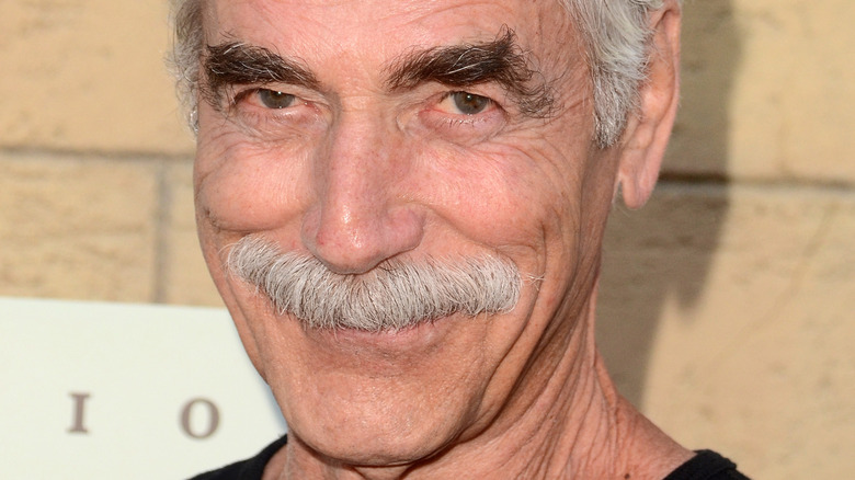 Sam Elliott smiles in a black shirt